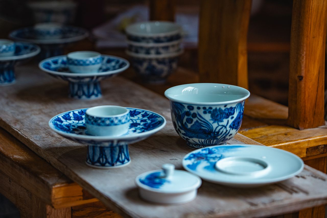 get-in-touch Elegant blue and white porcelain tableware set on a rustic wooden table indoors.