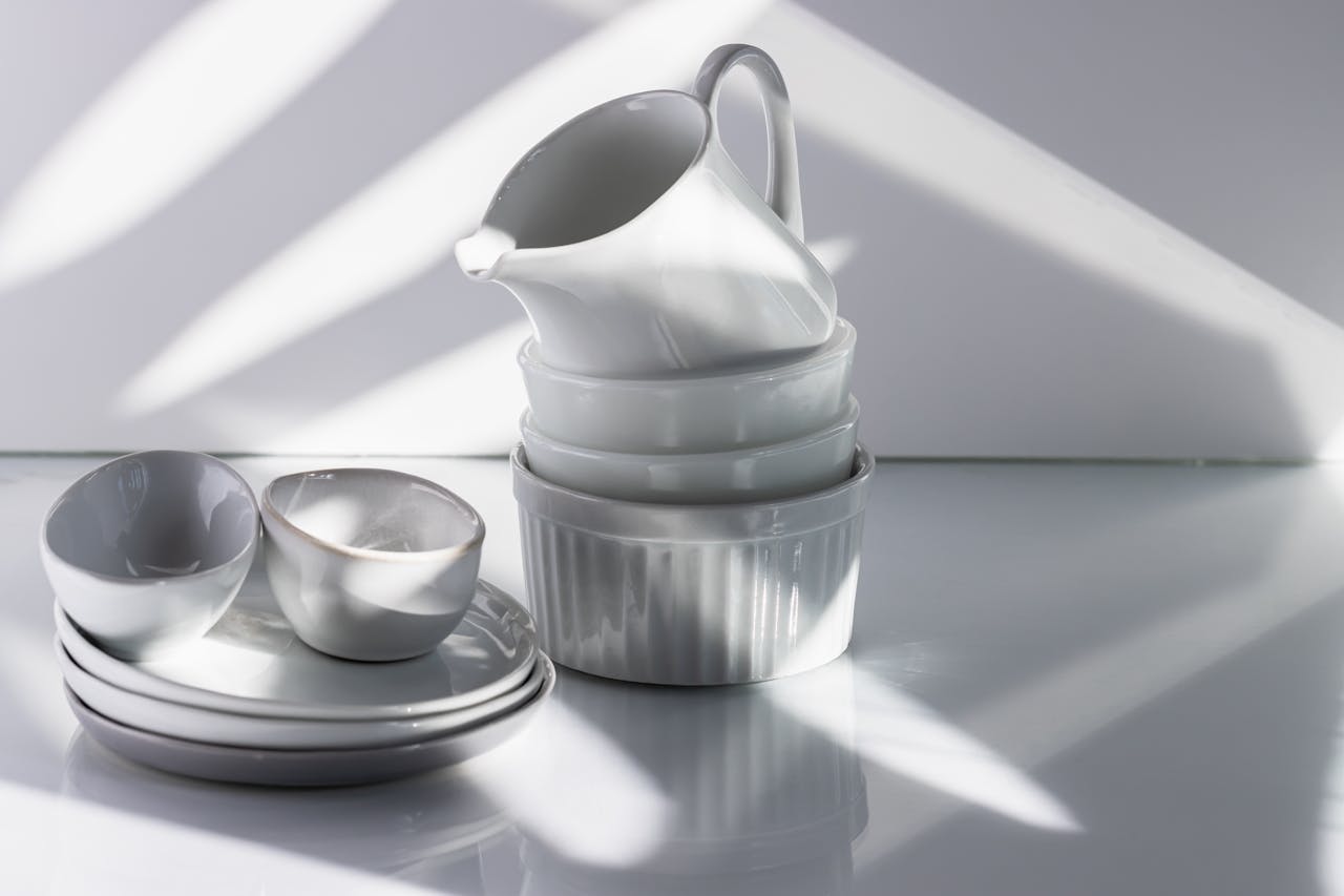 services-02 Elegant arrangement of white porcelain tableware with dramatic studio lighting and shadows.