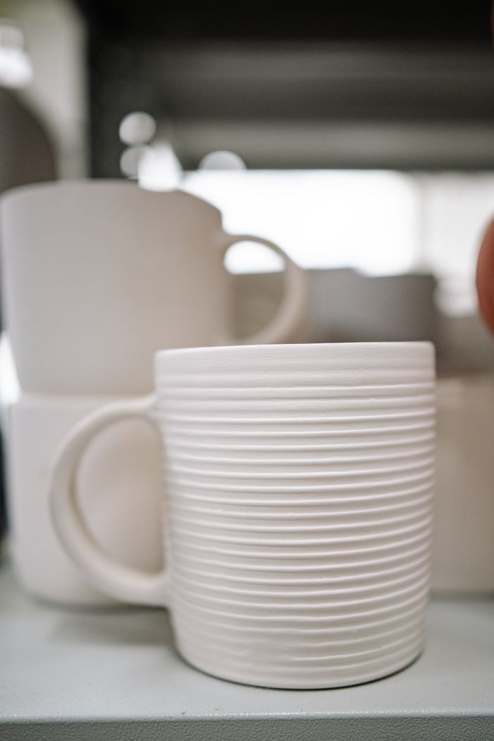 Detailed view of stacked white ceramic mugs showcasing their textured design indoors.