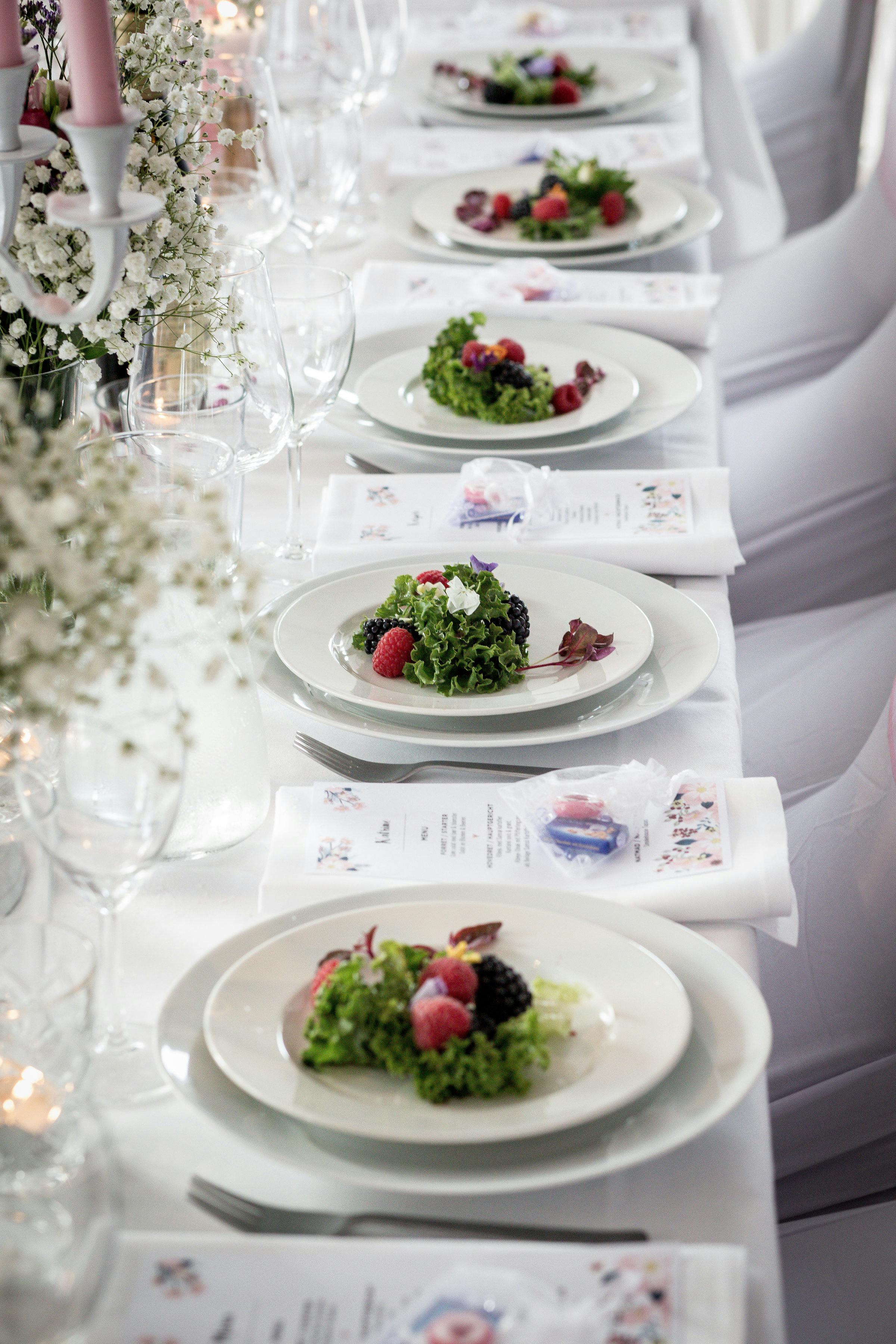 eleganckie-nakrycie-stolu-bankietowego-horeca Eleganckie nakrycie długiego stołu bankietowego z białą porcelaną premium, kryształowymi kieliszkami i dekoracjami kwiatowymi na przyjęcie weselne